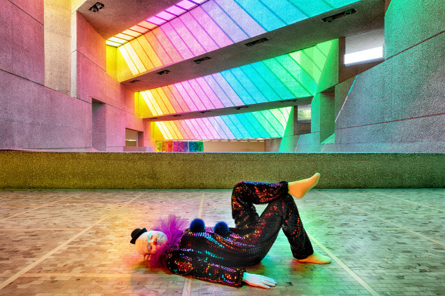 Installation view of colorful clown sculptures and rainbow colored windows by Ugo Rondinone