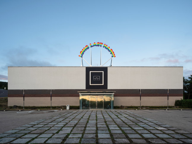 Installation view of outdoor neon sign saying long last happy by Ugo Rondinone