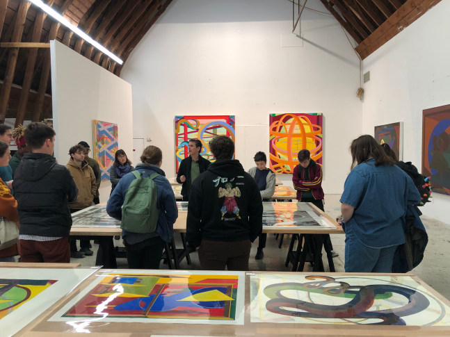 A group of students discuss colorful abstract prints and paintings by Al Held.