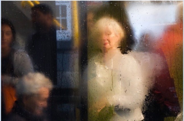 photograph through water of people waiting at a bus stop