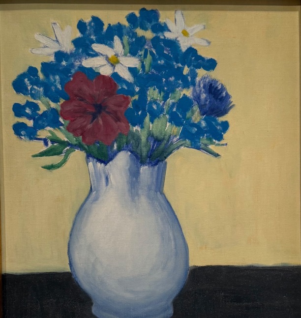 white vase with flowers and a red petunia on a brown table with a soft yellow background