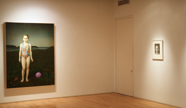 Photograph showing a corner view of an exhibition space, with one large framed painting and one small framed drawing hanging on white walls