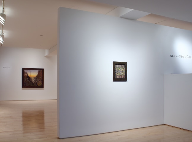 Photograph showing the front view of an exhibition space, with two paintings hung on white walls
