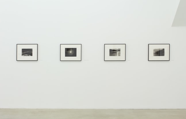 Photograph of four framed drawings on a white wall