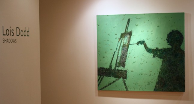 Photograph showing a view of an exhibition space, with one painting hanging on the wall, and wall text that reads &quot;Lois Dodd: Shadows&quot; on the wall to the left
