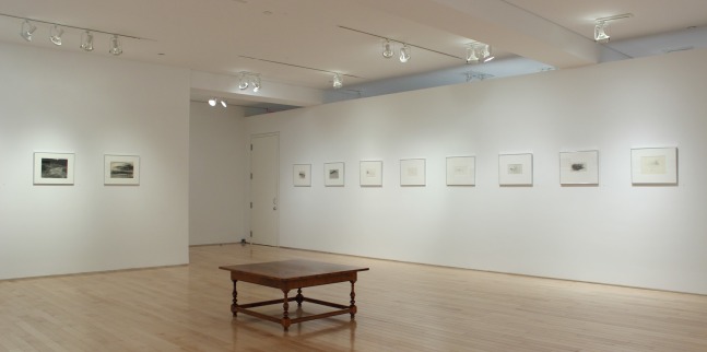 Photograph showing a corner view of an exhibition space, with ten framed drawings hanging on white walls