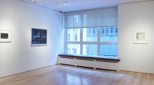 Photograph showing a corner view of an exhibition space, with three framed drawings hanging on white walls