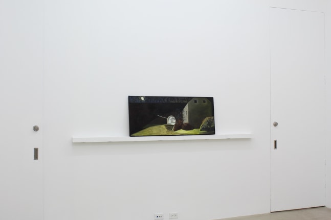 Photograph showing a view of an exhibition space, with one painting sitting on a shelf against a white wall