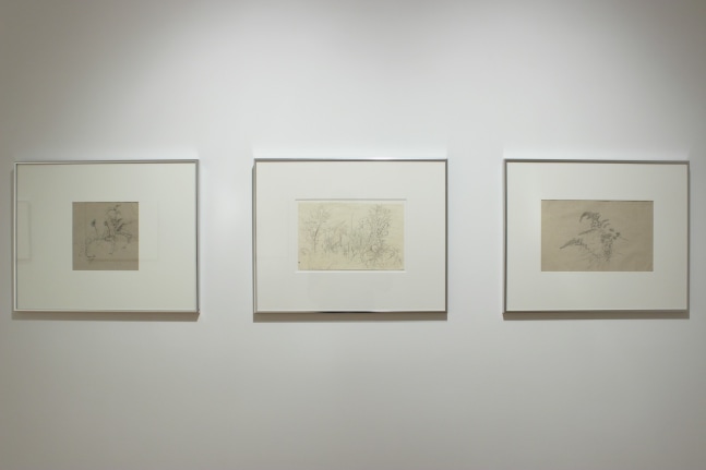 Photograph showing a detail view of an exhibition, with three framed drawings hanging on a white wall