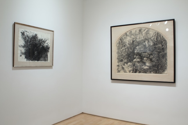 Photograph showing a corner view of an exhibition space with two paintings hanging on white walls