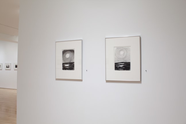 Photograph showing a view of an exhibition space, with two framed drawings hanging on a white wall