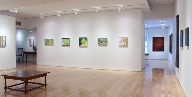 Photograph showing corner view of an exhibition space, with six painting hanging on white walls