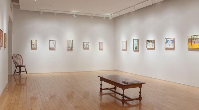 Photograph showing a corner view of an exhibition space, with eleven small paintings hanging on white walls
