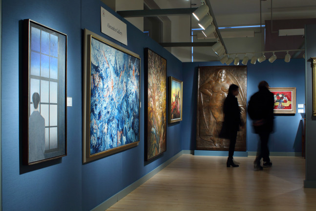 Photograph showing a corner view of an exhibition space, with six paintings hanging on blue walls