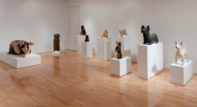 Photograph showing a corner view of an exhibition space, with various sculptures on pedestals throughout the gallery