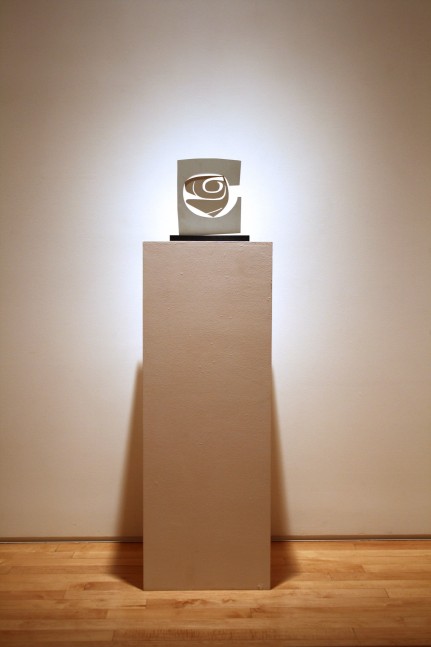 Photograph showing a view of an exhibition, with a small sculpture on top of a pedestal