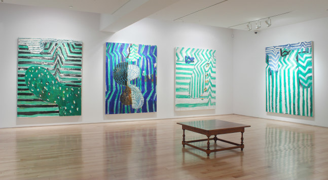 Photograph showing a corner view of an exhibition space, with four large paintings hanging on white walls
