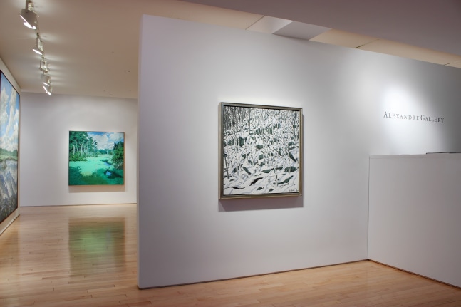 Photograph showing a view of an exhibition space, with a painting hanging on a white wall and the exhibition continuing in the background