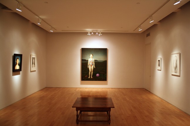 Photograph showing a view of an exhibition space, with one large framed painting, a smaller framed painting, and three framed drawings hanging on white walls