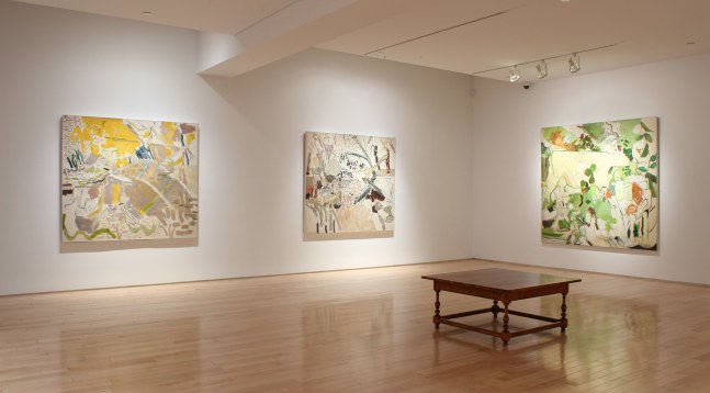 Photograph showing a corner view of an exhibition space, with three paintings hanging on white walls
