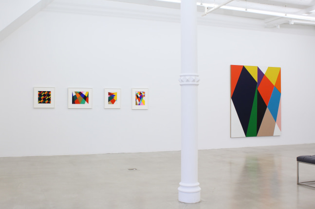 Photograph showing a view of an exhibition space, with five paintings hanging on a white wall