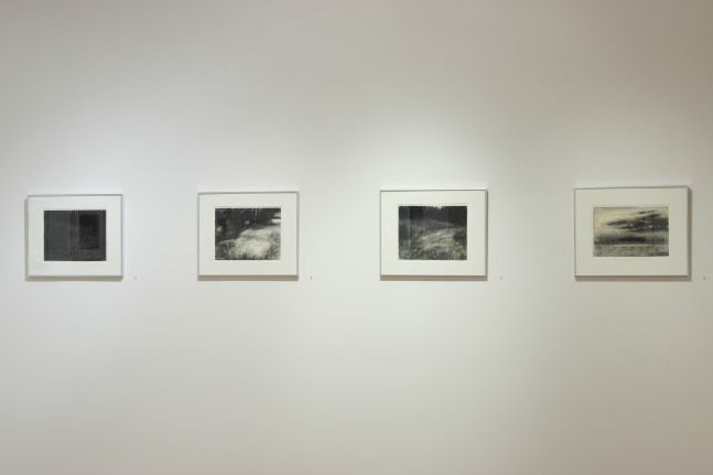 Photograph showing a view of an exhibition space, with four framed drawings hanging on a white wall