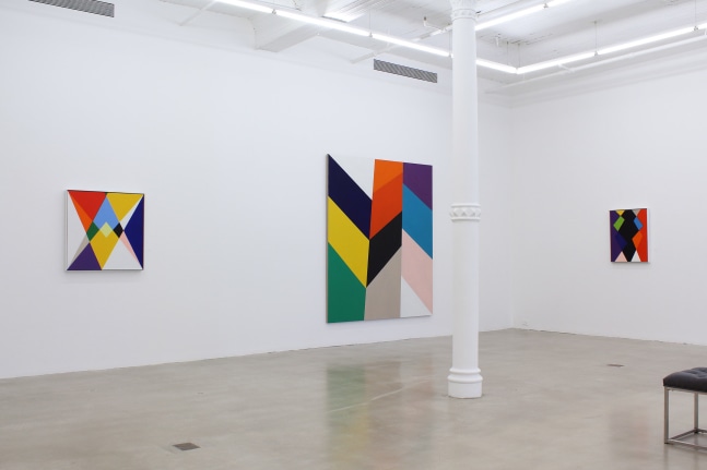 Photograph showing a corner view of an exhibition space, with three paintings hanging on white walls