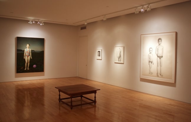 Photograph showing a corner view of an exhibition space, with one large framed painting, a large framed drawing, and two smaller framed drawings hanging on white walls