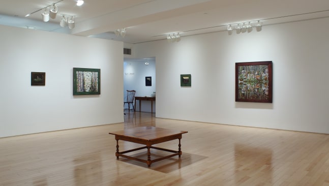 Photograph showing a corner view of an exhibition space, with five paintings hung on white walls