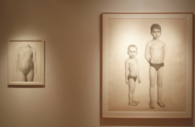 Photograph showing a view of an exhibition, with one framed drawing and one smaller framed drawing hanging on a wall