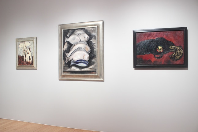 Photograph showing a view of an exhibition space, with three paintings hanging on a white wall