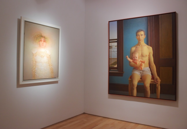 Photograph showing a corner view of an exhibition space with two paintings hanging on a white wall