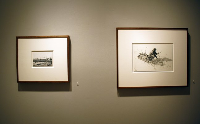 Photograph showing a view of an exhibition, with two small framed drawings hanging on a grey wall