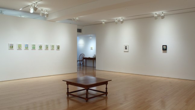 Photograph showing a corner view of an exhibition space, with eleven small paintings hung on white walls