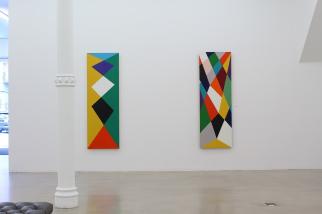 Photograph showing a view of an exhibition space, with two paintings hanging on a white wall