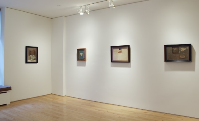 Photograph showing a corner view of an exhibition space with four paintings hanging on white walls