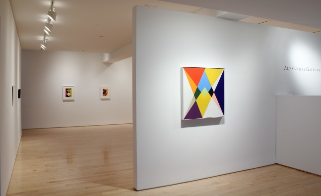 Photograph showing a front view of an exhibition space, with three paintings hung on white walls