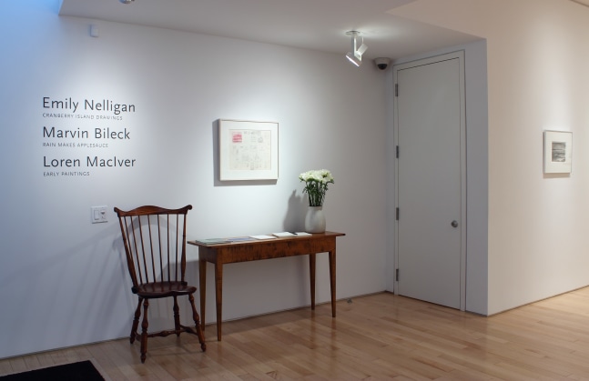 Photograph showing a view of the beginning of an exhibition, with one painting hanging over a table and chair