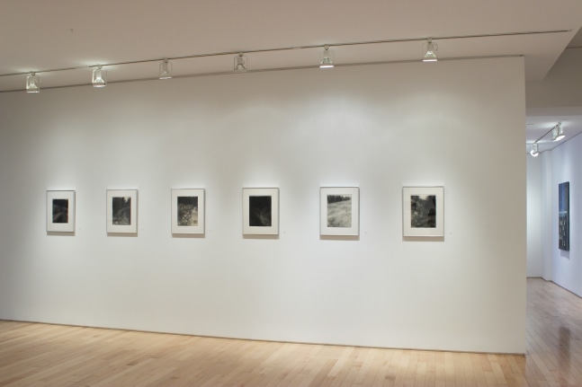 Photograph showing a view of an exhibition space, with six framed drawings hanging on a white wall