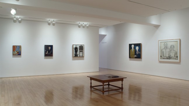 Photograph showing a corner view of an exhibition space, with five paintings hung on white walls