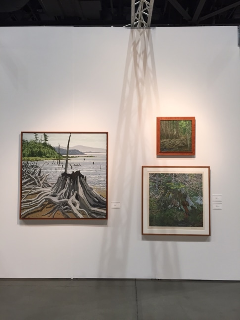 Photograph showing a view of an exhibition space, with three paintings of various sizes hanging on a white wall