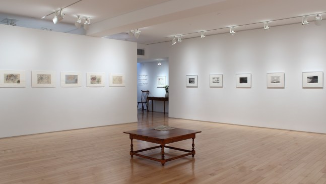 Photograph showing a corner view of an exhibition space, with ten drawings hanging on white walls.