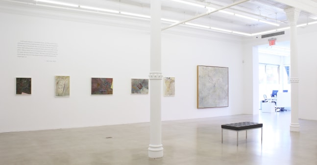 Photograph showing a view of an exhibition space, with six paintings hanging on a white wall