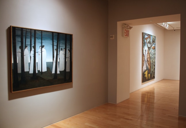 Photograph showing a view of an exhibition, with two large framed paintings hanging on the walls