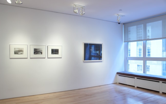 Photograph showing a view of an exhibition space, with four framed drawings hanging on a white wall