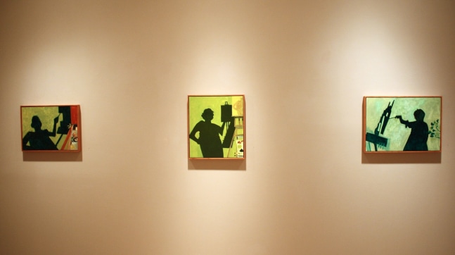 Photograph showing a view of an exhibition, with three small framed paintings hanging on a white wall