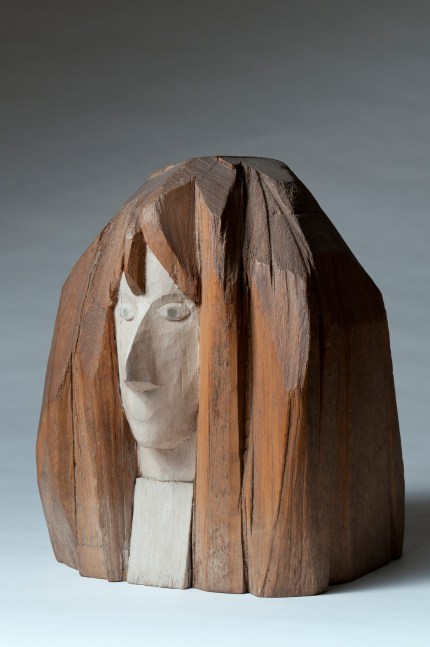 Three-quarter view of a wood sculpture of the head of a woman from the neck up