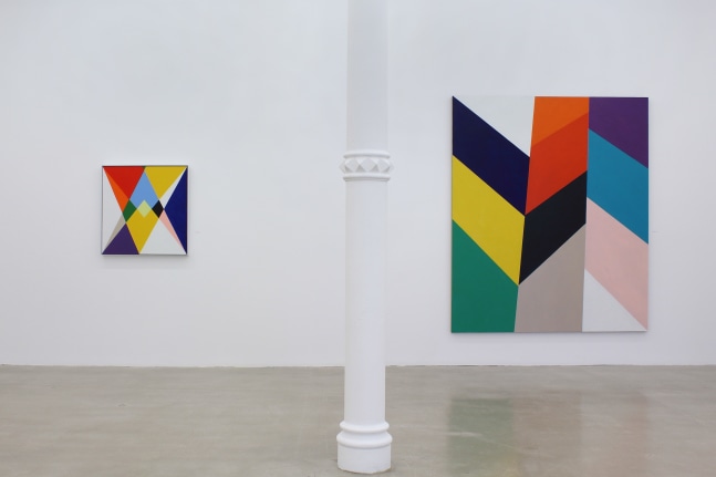 Photograph showing a view of an exhibition space, with two paintings hanging on a white wall