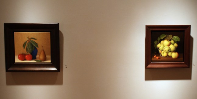 Photograph showing a view of an exhibition, with two small framed paintings hanging on a grey wall