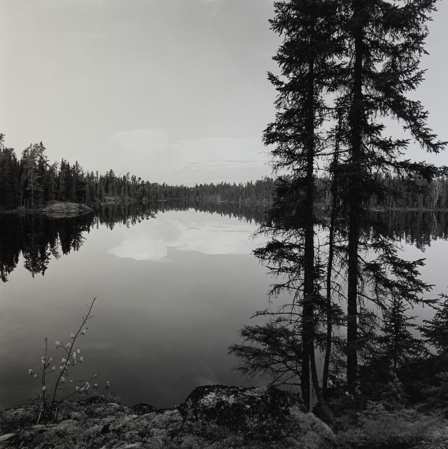 Black and white photograph of a body of water surrounded by trees